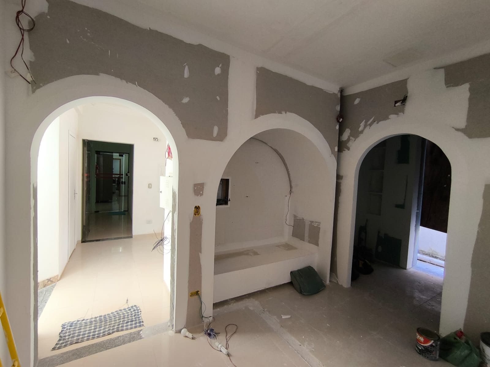 Três arcos em gesso acabados abrindo para os ambientes de uma residência